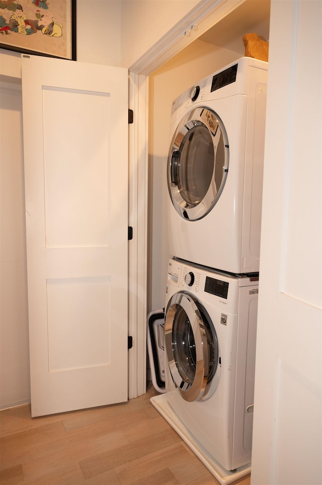 clothes washing area featuring light wood-type flooring and stacked washer / drying machine