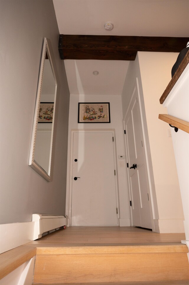 hall featuring beamed ceiling, hardwood / wood-style floors, and a baseboard radiator