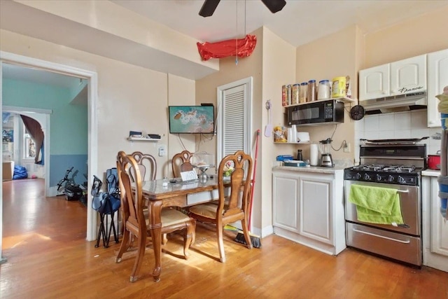 kitchen with gas stove, tasteful backsplash, white cabinets, ceiling fan, and light hardwood / wood-style flooring