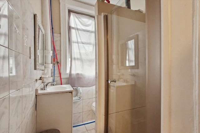 bathroom featuring tile walls, vanity, toilet, and a shower with shower door