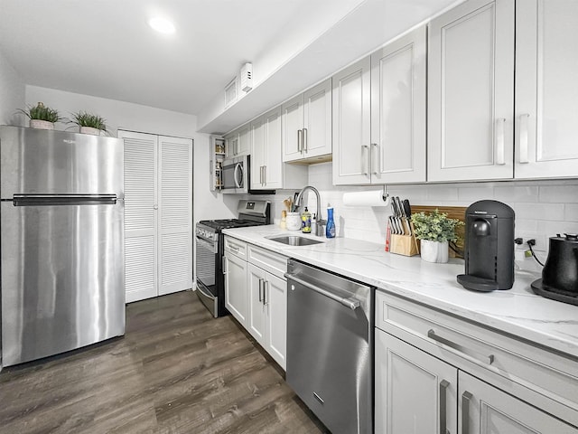 kitchen with sink, dark wood-type flooring, stainless steel appliances, light stone countertops, and white cabinets