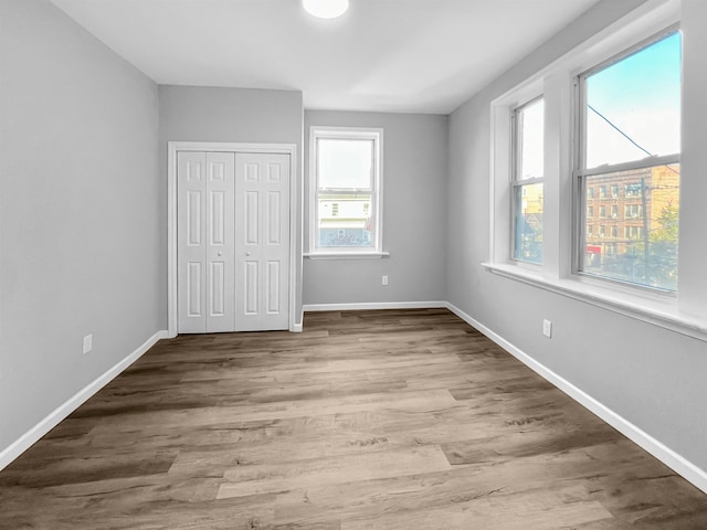 unfurnished bedroom featuring a closet, hardwood / wood-style flooring, and multiple windows