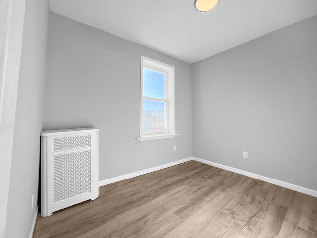 spare room featuring radiator and wood-type flooring