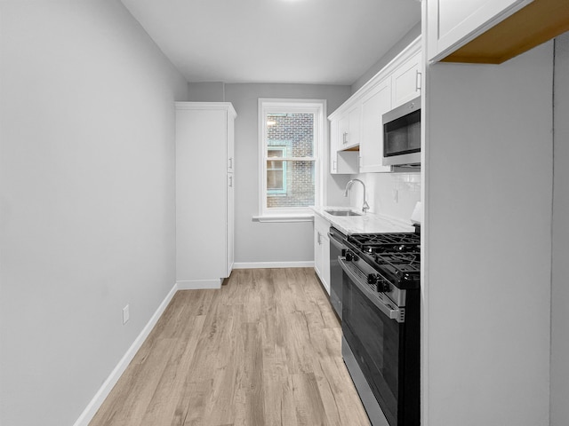 kitchen featuring white cabinets, sink, light hardwood / wood-style flooring, decorative backsplash, and stainless steel appliances