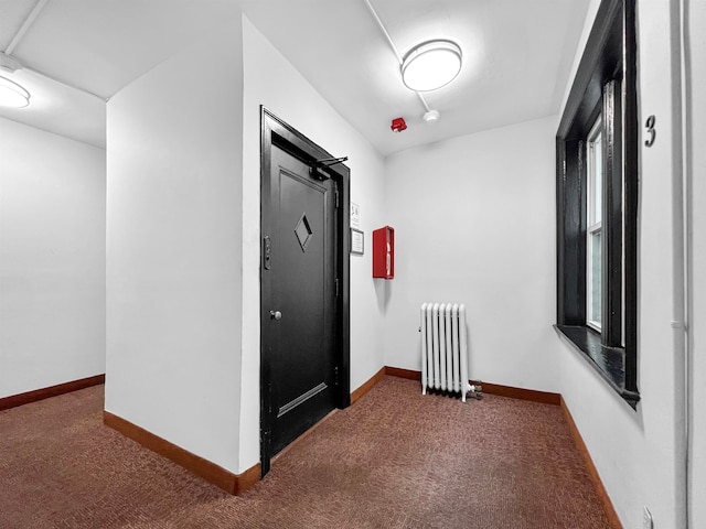 corridor with radiator heating unit and dark colored carpet