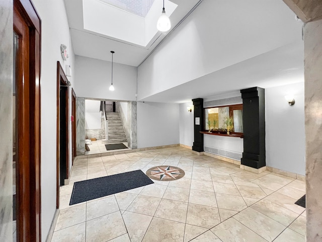 interior space featuring light tile patterned flooring, a high ceiling, and a skylight