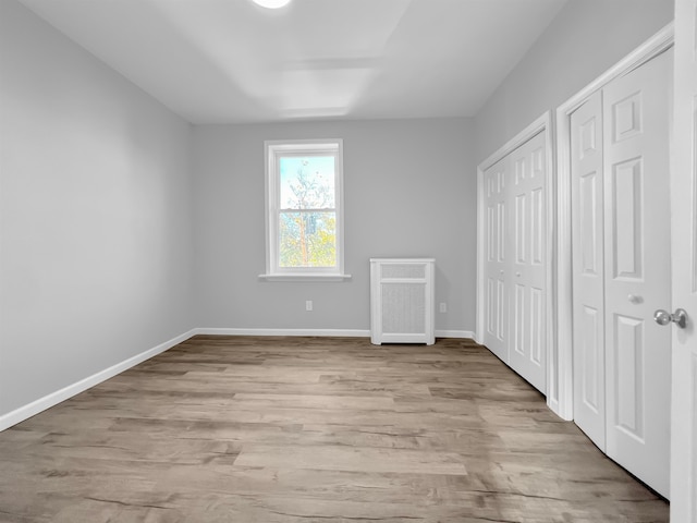 unfurnished bedroom with light hardwood / wood-style floors and multiple closets