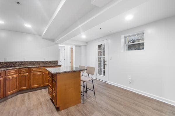 2608 Kennedy Blvd Unit 1, Union City, NJ 07087 - kitchen featuring a kitchen breakfast bar, light wood-style floors, brown cabinets, a center island, and dark stone countertops