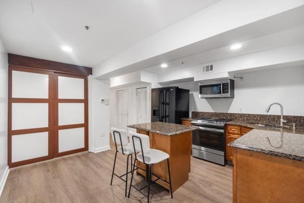 2608 Kennedy Blvd Unit 1, Union City, NJ 07087 - kitchen featuring stainless steel appliances, a center island, a kitchen breakfast bar, light wood-style floors, and dark stone countertops