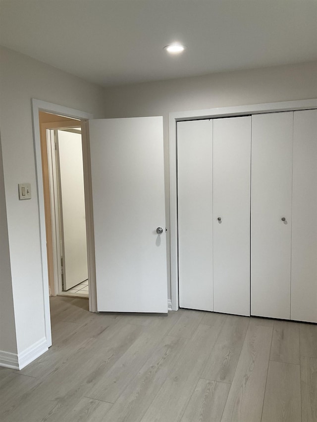 unfurnished bedroom with light wood-type flooring and a closet