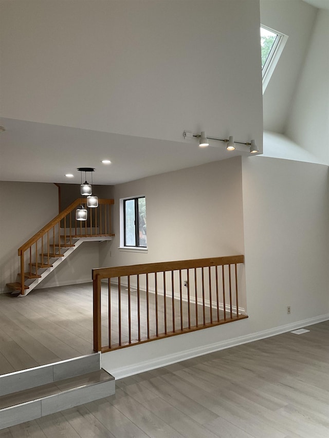 stairway featuring wood-type flooring and lofted ceiling with skylight