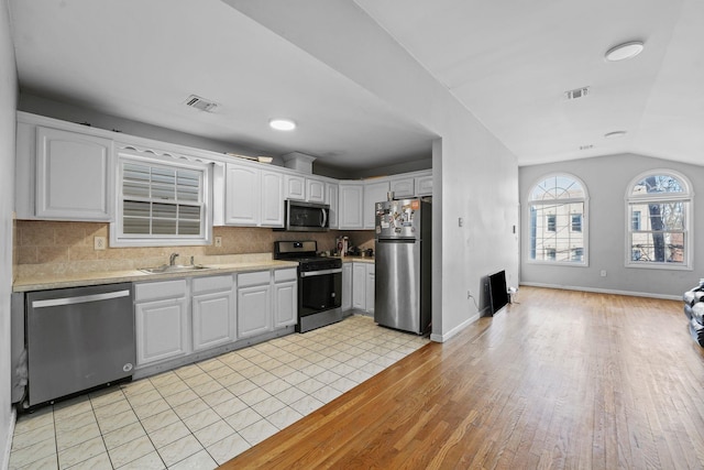 kitchen featuring stainless steel appliances, a sink, visible vents, white cabinets, and light countertops