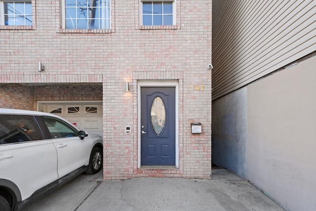 property entrance with a garage and brick siding