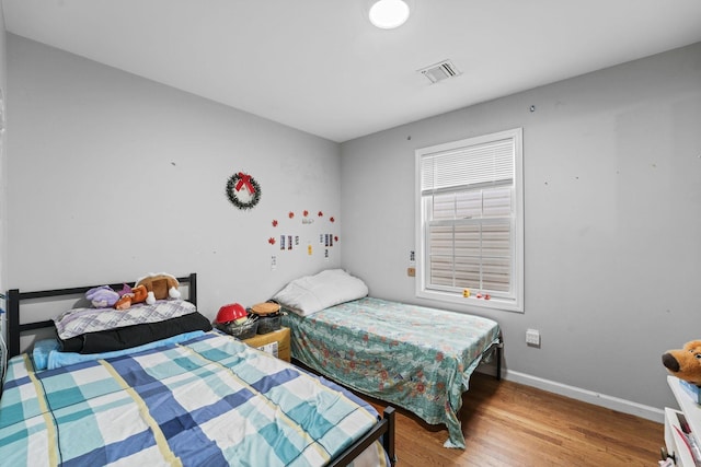 bedroom featuring visible vents, baseboards, and wood finished floors