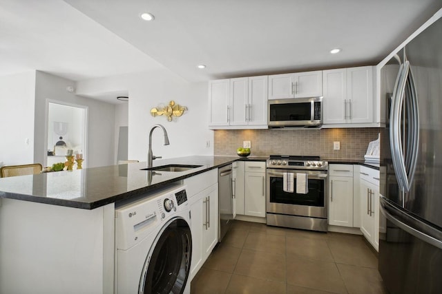 kitchen featuring stainless steel appliances, white cabinetry, a sink, washer / dryer, and dark tile patterned floors