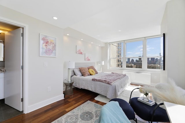 bedroom with a view of city, dark wood-style flooring, baseboards, and recessed lighting