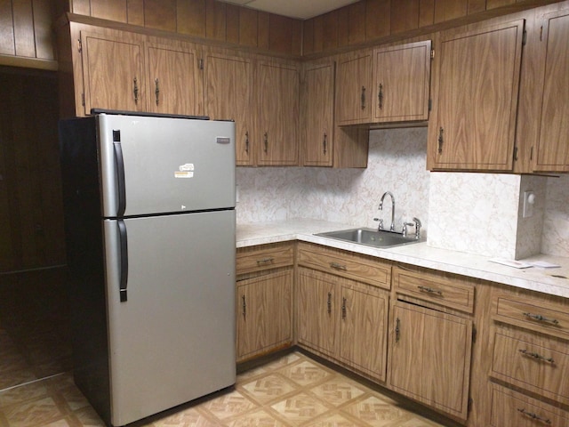 kitchen featuring a sink, tasteful backsplash, light countertops, and freestanding refrigerator