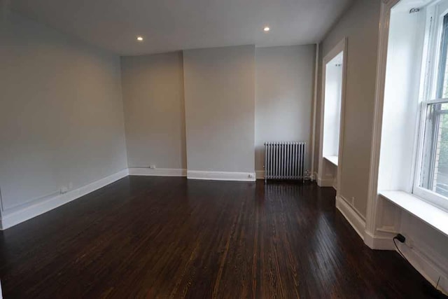 spare room featuring dark wood finished floors, radiator, recessed lighting, and baseboards