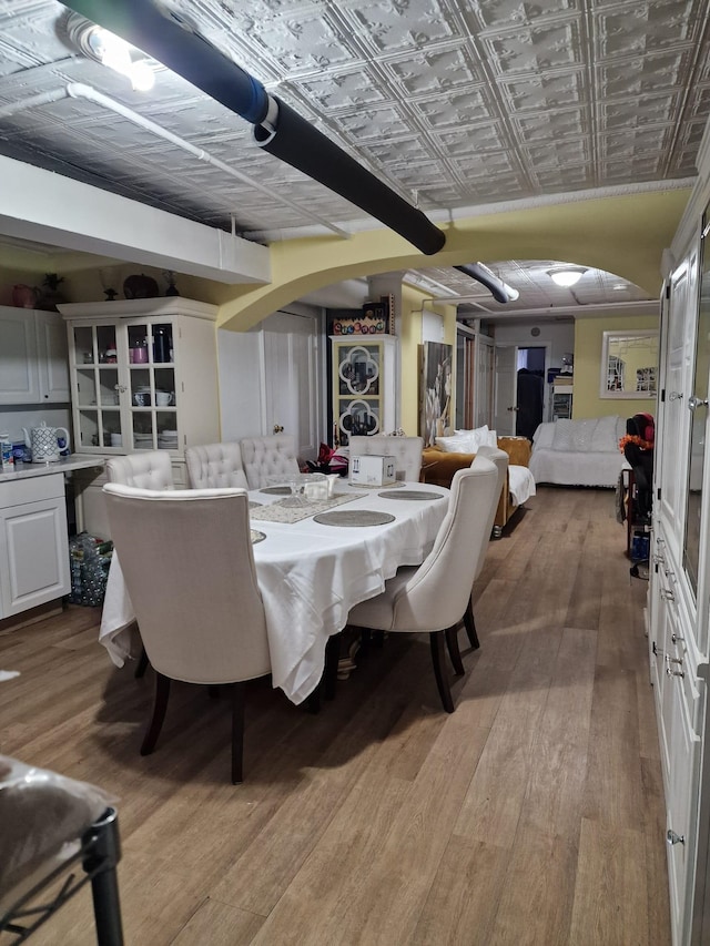 dining room featuring light wood-type flooring, an ornate ceiling, and arched walkways