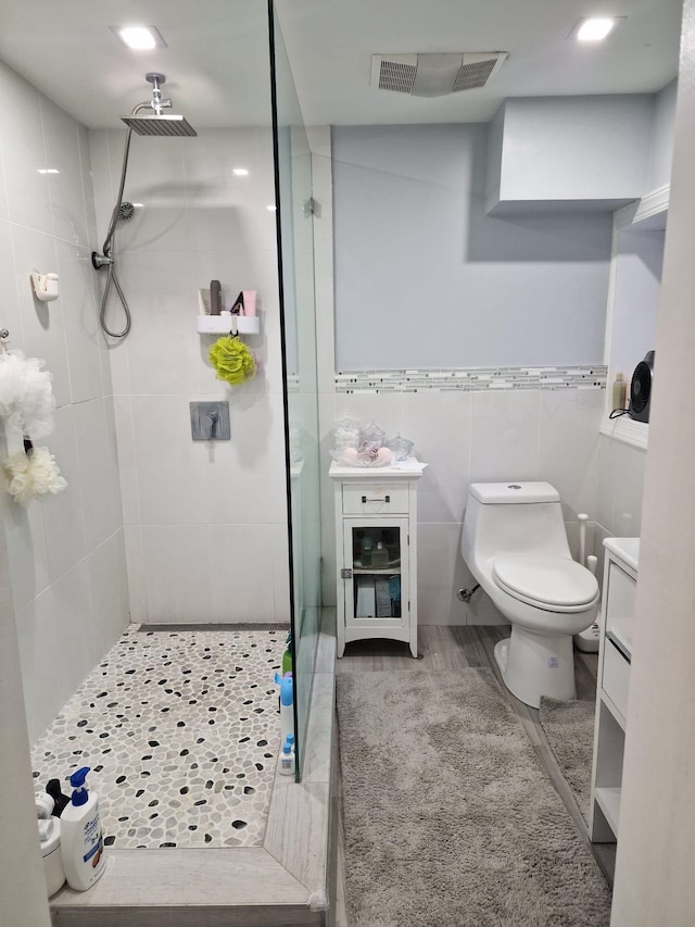 bathroom with vanity, visible vents, a stall shower, tile walls, and toilet