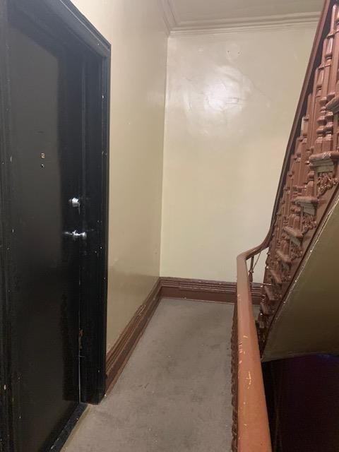 corridor featuring baseboards, stairs, and crown molding