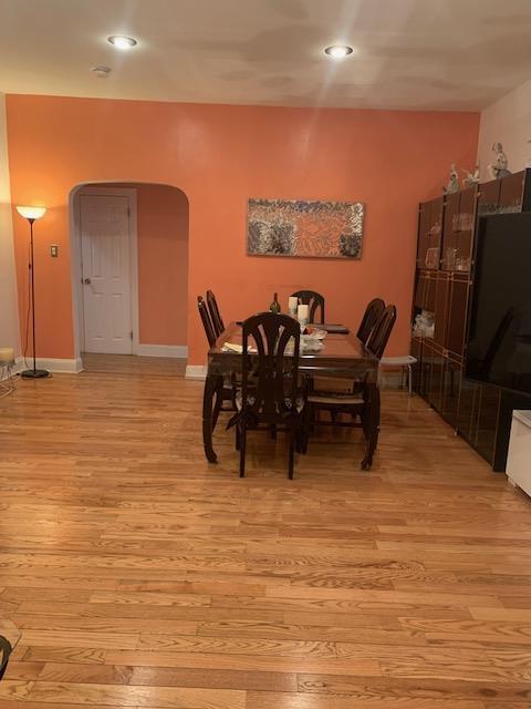 dining area featuring baseboards, arched walkways, and light wood-style flooring