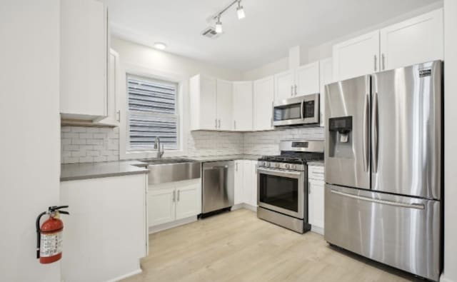 107 Laidlaw Ave Unit 2, Jersey City, NJ 07306 - kitchen featuring stainless steel appliances, a sink, white cabinetry, decorative backsplash, and light wood-style floors