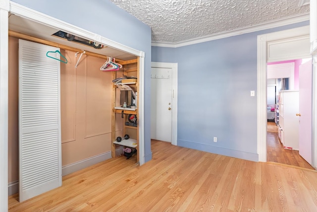 unfurnished bedroom with ornamental molding, light hardwood / wood-style floors, and a textured ceiling