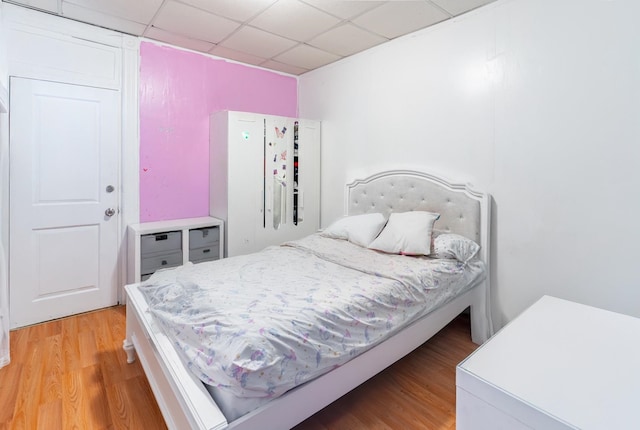 bedroom with a drop ceiling and hardwood / wood-style flooring