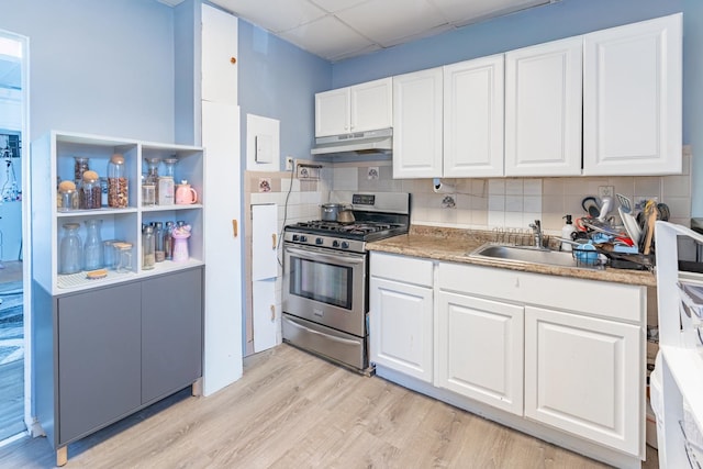 kitchen featuring white cabinetry, light wood-type flooring, stainless steel gas range, decorative backsplash, and sink