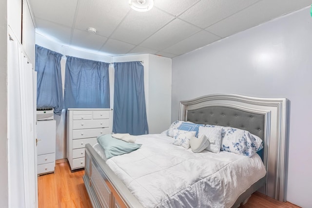 bedroom featuring light hardwood / wood-style floors, a paneled ceiling, and cooling unit