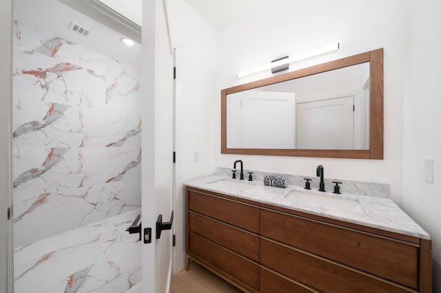 bathroom featuring tiled shower and vanity