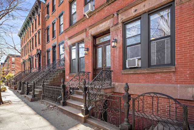 view of exterior entry with brick siding and cooling unit