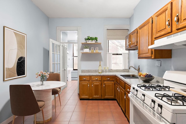 kitchen featuring brown cabinetry, white range with gas stovetop, a sink, light countertops, and under cabinet range hood