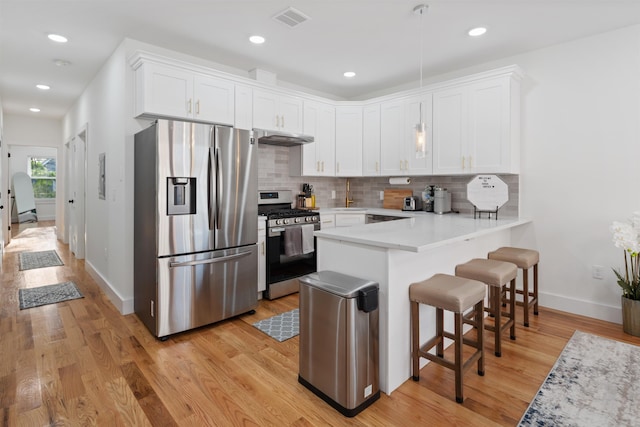 185 Gates Ave, Jersey City, NJ 07305 - kitchen featuring visible vents, baseboards, a peninsula, under cabinet range hood, and stainless steel appliances
