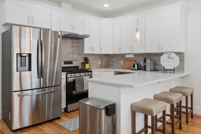 185 Gates Ave, Jersey City, NJ 07305 - kitchen featuring a kitchen breakfast bar, a sink, a peninsula, under cabinet range hood, and stainless steel appliances