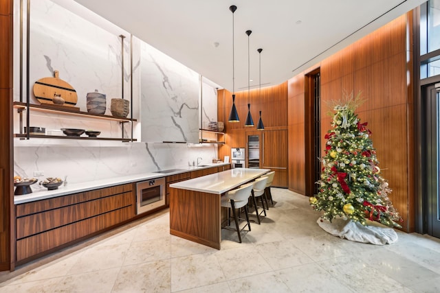 kitchen with oven, a kitchen island, a kitchen breakfast bar, decorative light fixtures, and decorative backsplash