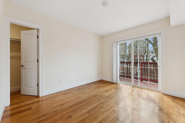 spare room with baseboards and wood finished floors