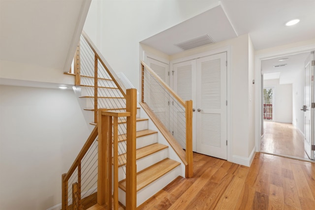 staircase featuring recessed lighting, wood finished floors, visible vents, and baseboards