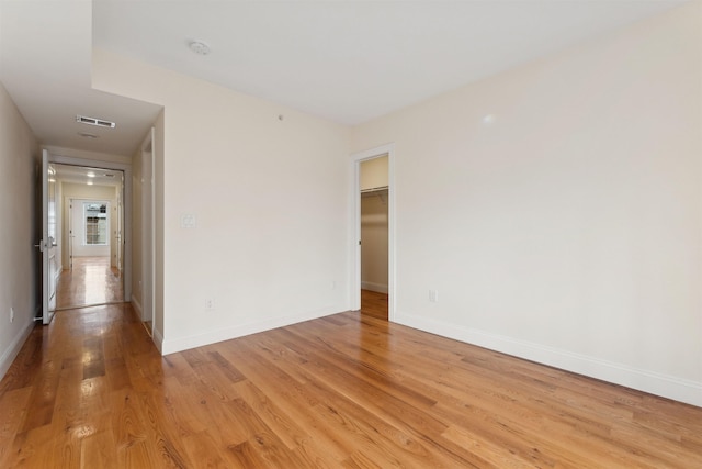 unfurnished room with light wood finished floors, visible vents, and baseboards