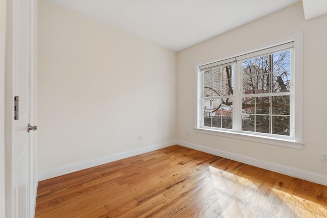 spare room featuring a wealth of natural light, baseboards, and light wood-style flooring