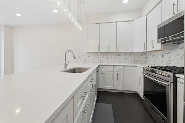 kitchen with tasteful backsplash, light stone countertops, stainless steel appliances, white cabinetry, and a sink