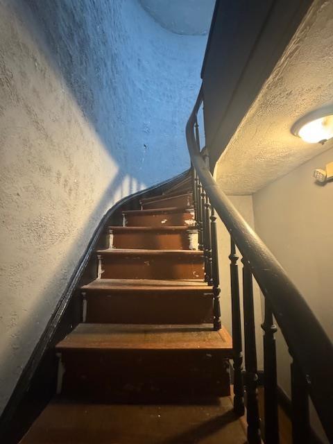 stairway featuring a textured ceiling