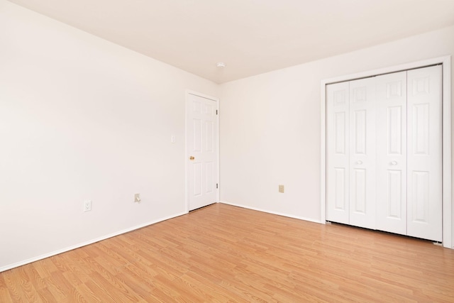 unfurnished bedroom with baseboards, a closet, and light wood-style floors