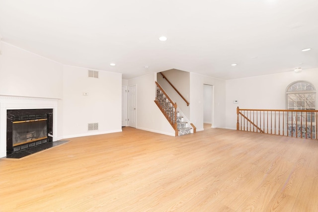 unfurnished living room featuring a fireplace with flush hearth, visible vents, and wood finished floors