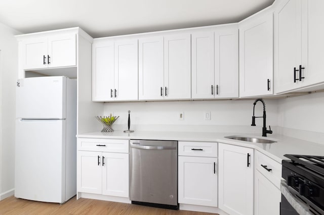 kitchen featuring stainless steel appliances, a sink, white cabinets, light countertops, and light wood-type flooring