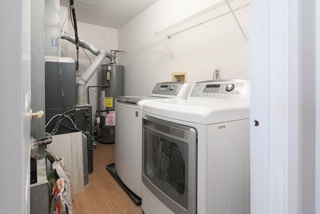 clothes washing area with light wood-style floors, washer and dryer, laundry area, and water heater