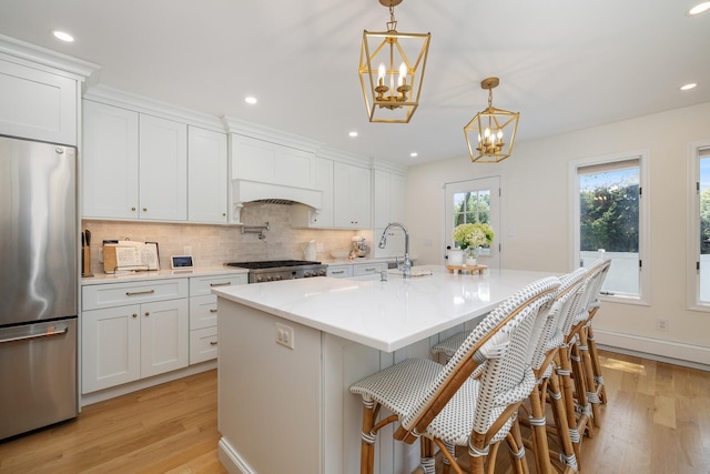 11 Dean Ct, Rutherford, NJ 07070 - kitchen with stainless steel fridge, a chandelier, decorative backsplash, light wood-type flooring, and light countertops