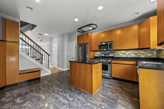 235 Price Ct, West New York, NJ 07093 - kitchen featuring appliances with stainless steel finishes, a kitchen island, dark countertops, tasteful backsplash, and brown cabinetry