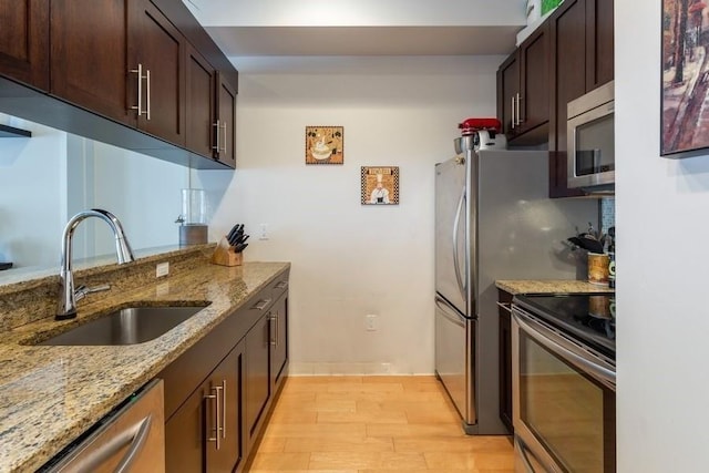 102 Tidewater St Unit 2B, Jersey City, NJ 07302 - kitchen featuring stainless steel appliances, a sink, light wood-type flooring, light stone counters, and dark brown cabinetry